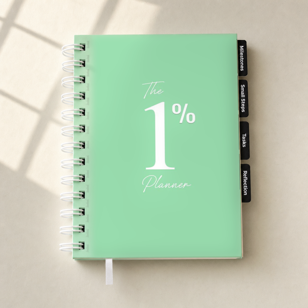 A mint green spiral-bound planner titled 'The 1% Planner' with white text, shown on a light beige surface with soft window shadow overlays. The planner has black tabs on the right side labeled 'Milestones', 'Small Steps', 'Tasks', and 'Reflection'.