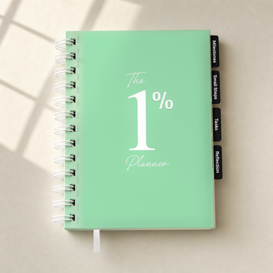 A mint green spiral-bound planner titled 'The 1% Planner' with white text, shown on a light beige surface with soft window shadow overlays. The planner has black tabs on the right side labeled 'Milestones', 'Small Steps', 'Tasks', and 'Reflection'.